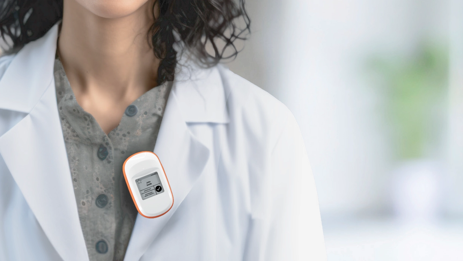 Primer plano (detalle) de una médica portando un dosímetro Instadose a la altura del pecho.